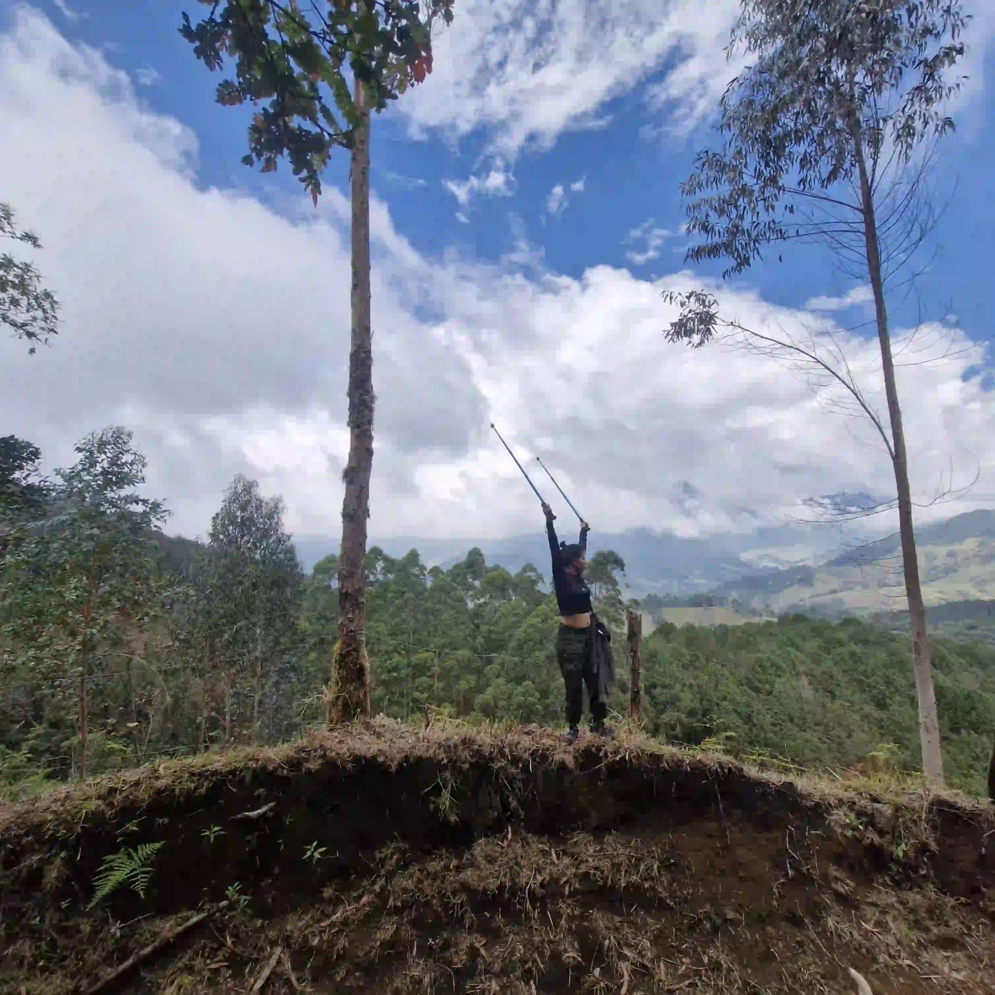 Caminante con los bastones de trekking en un punto elevado del Camino Nacional, rodeado de paisaje montañoso.